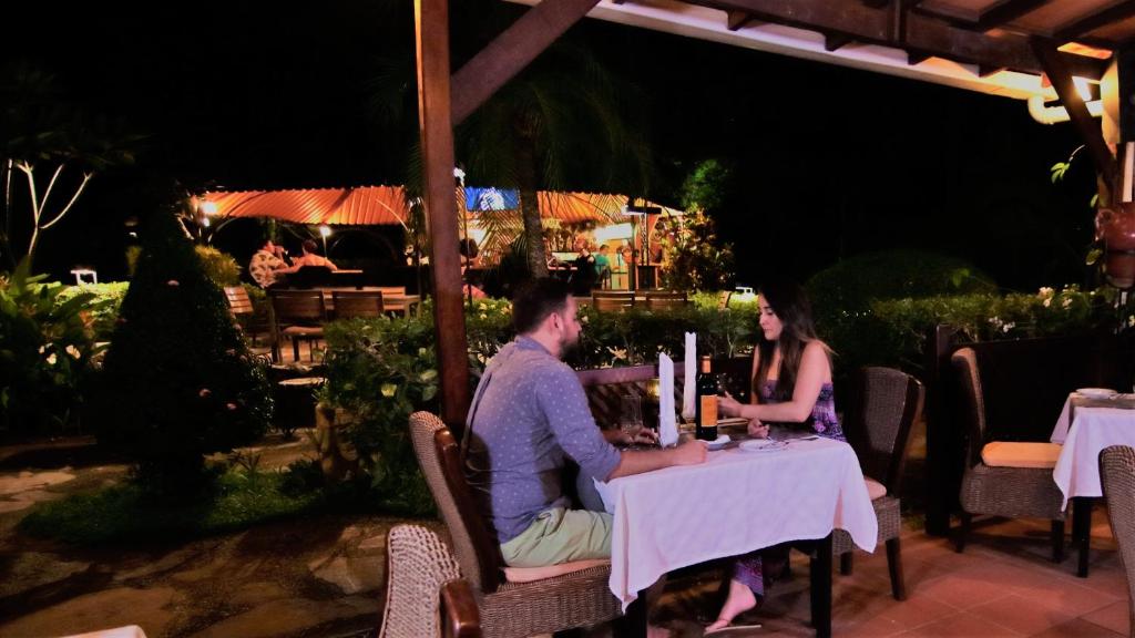 A girl and boy enjoying a dinner together at Playa Hermosa, with a scenic view.