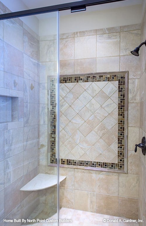 The walk-in shower has wrought iron fixtures, an inset shelf, and a corner seat.