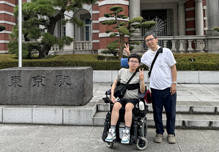 夏休みの東京旅行中に、東京駅前で記念撮影をする、普段車いすで生活している中学生の坂本篤宣くん