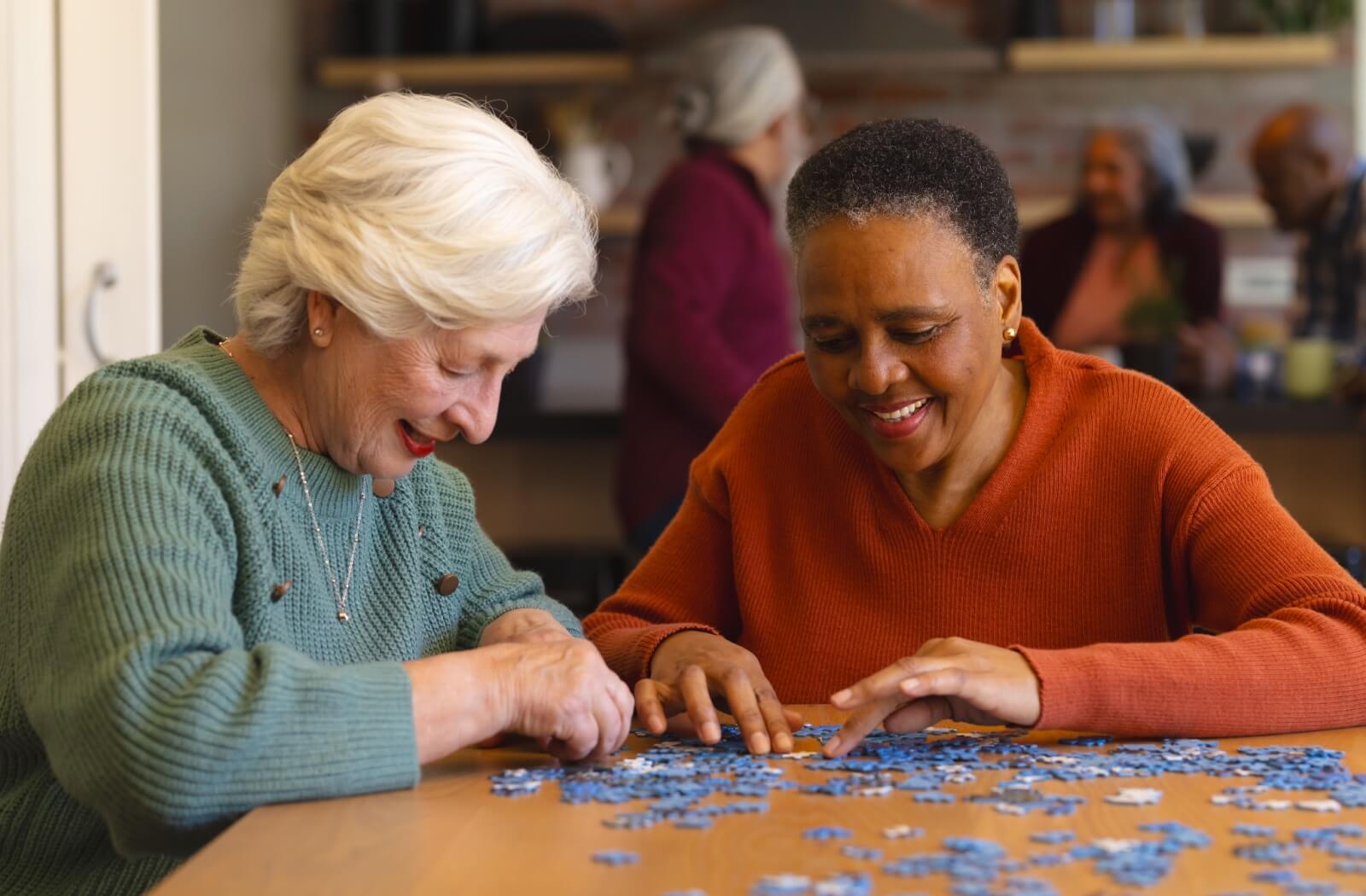 Two seniors working together to complete a puzzle.