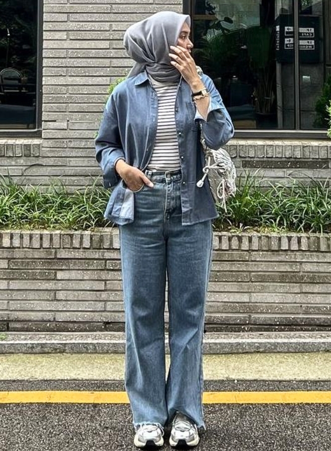 Wanita dengan celana denim dan jilbab abu-abu.