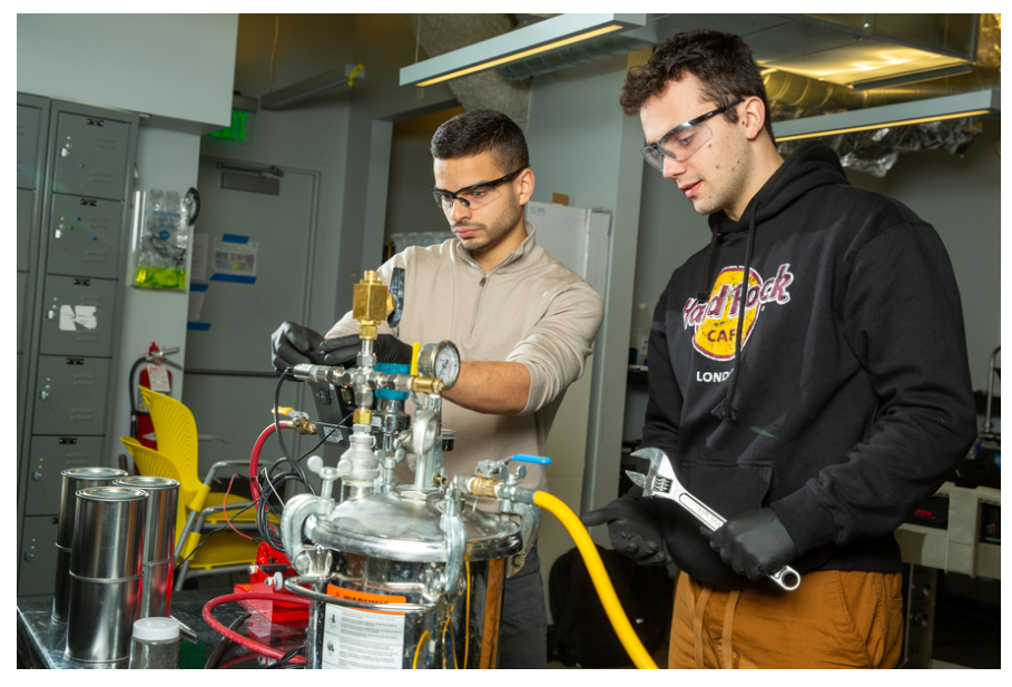 A couple of men working on a machine

Description automatically generated