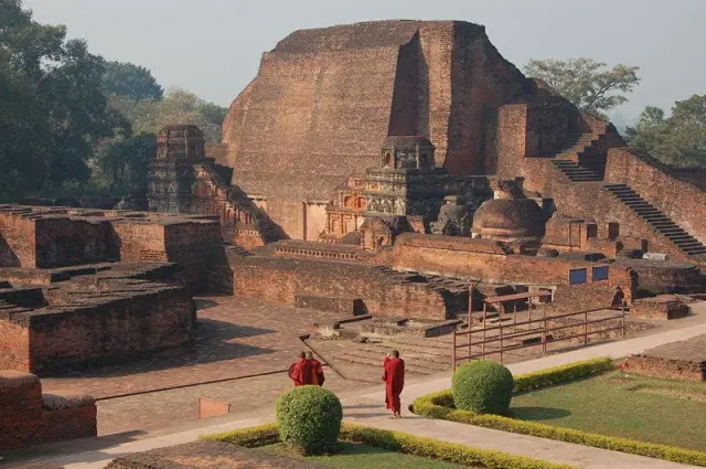 A group of people standing in front of a large brick building

Description automatically generated