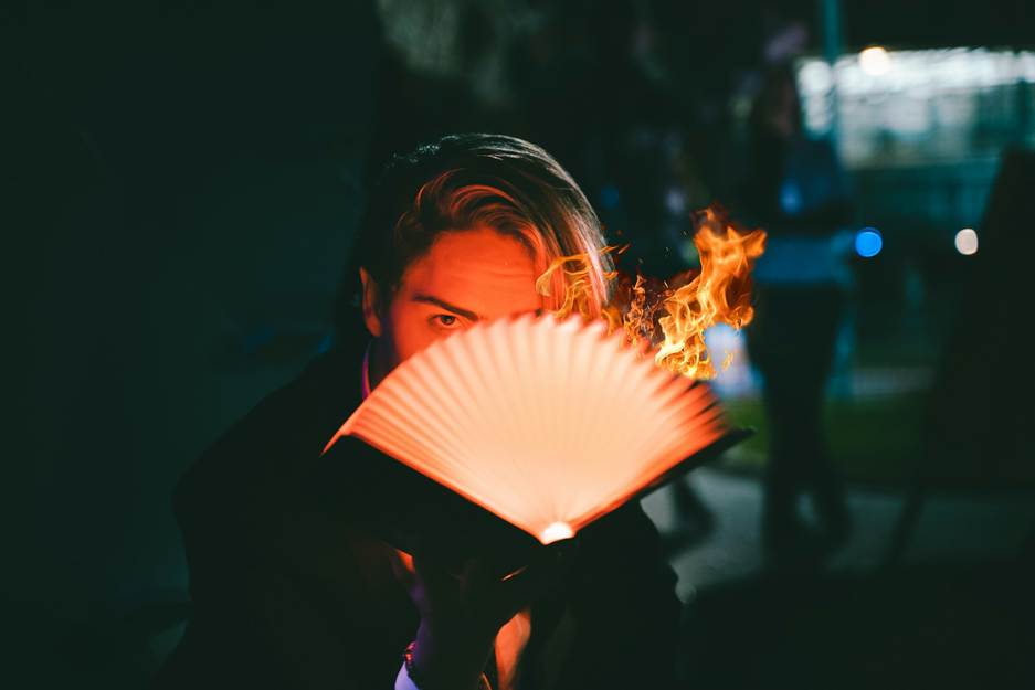 A person holding a book with a light on his faceAI-generated content may be incorrect.