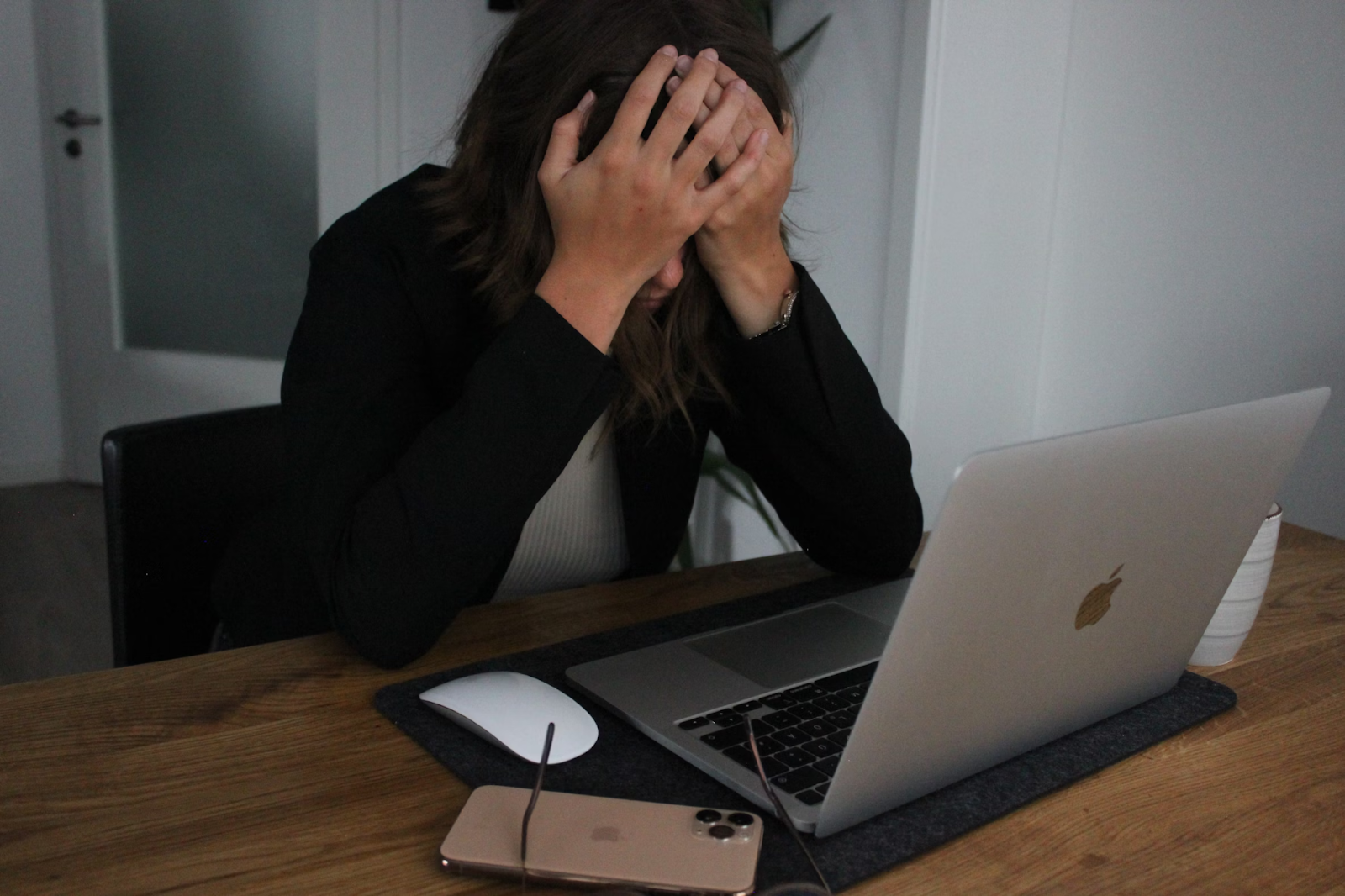 Woman with hands over her face and a laptop