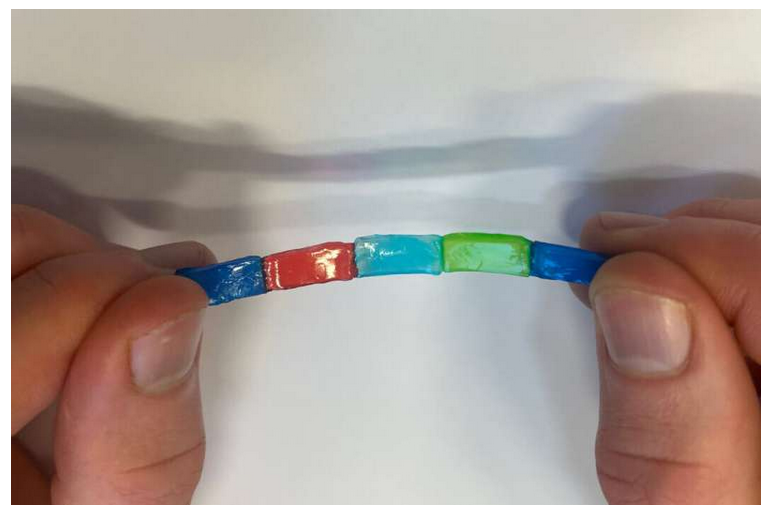 A close-up of a hand holding a colorful bead

Description automatically generated