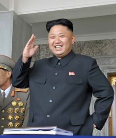 This contain an image of  Kim Jong-un on black suit with his hand up