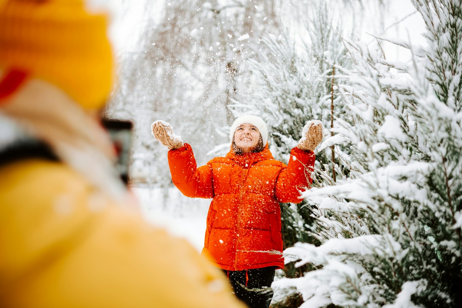 A woman in a red coat smiles with falling snow