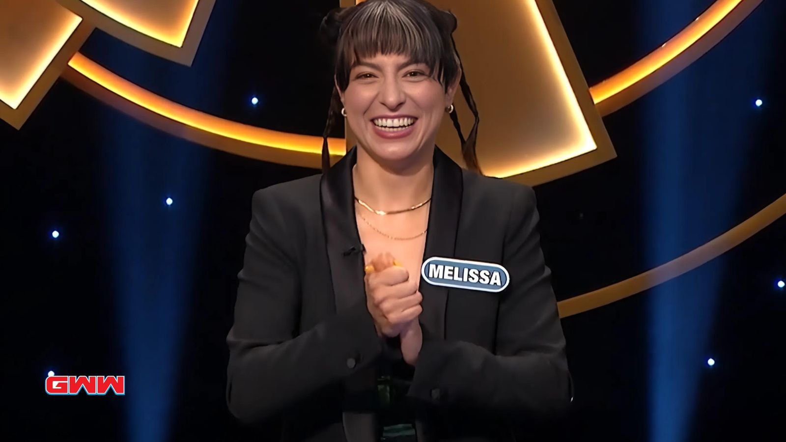 Contestant Melissa smiling on a game show stage, dressed in black.