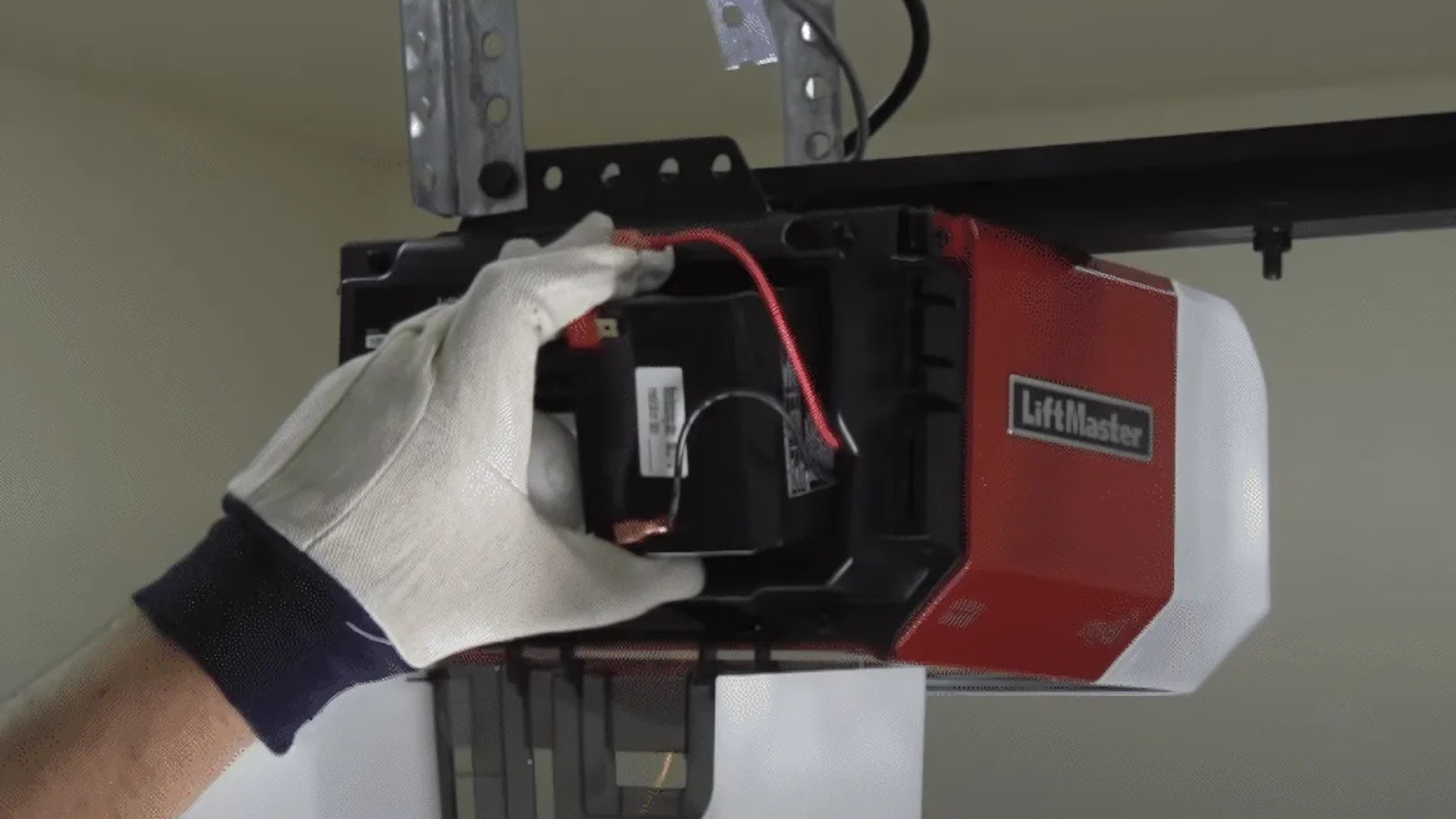 A technician installing a new battery on a LiftMaster garage door opener.