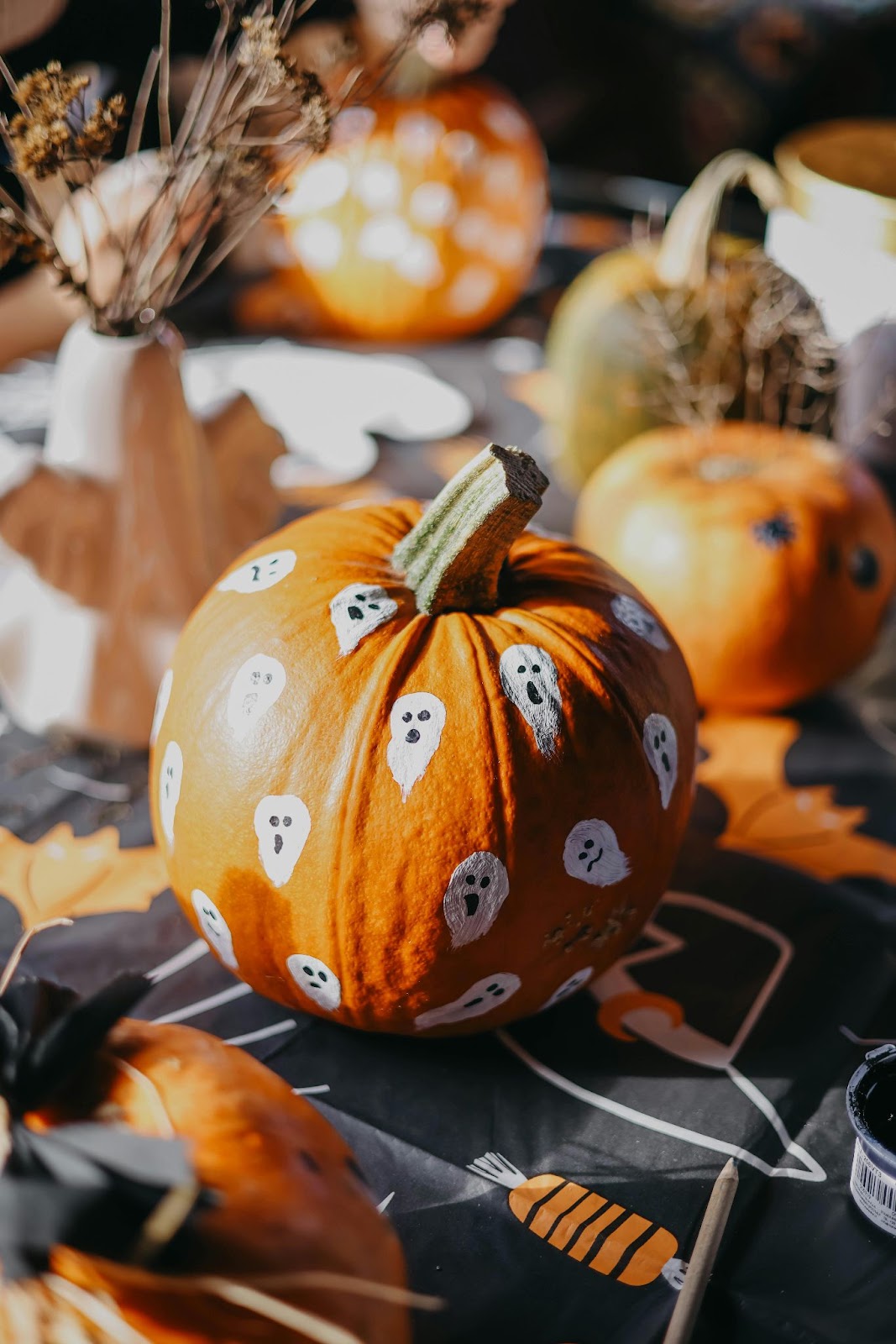 A small orange pumpkin painted with white ghosts