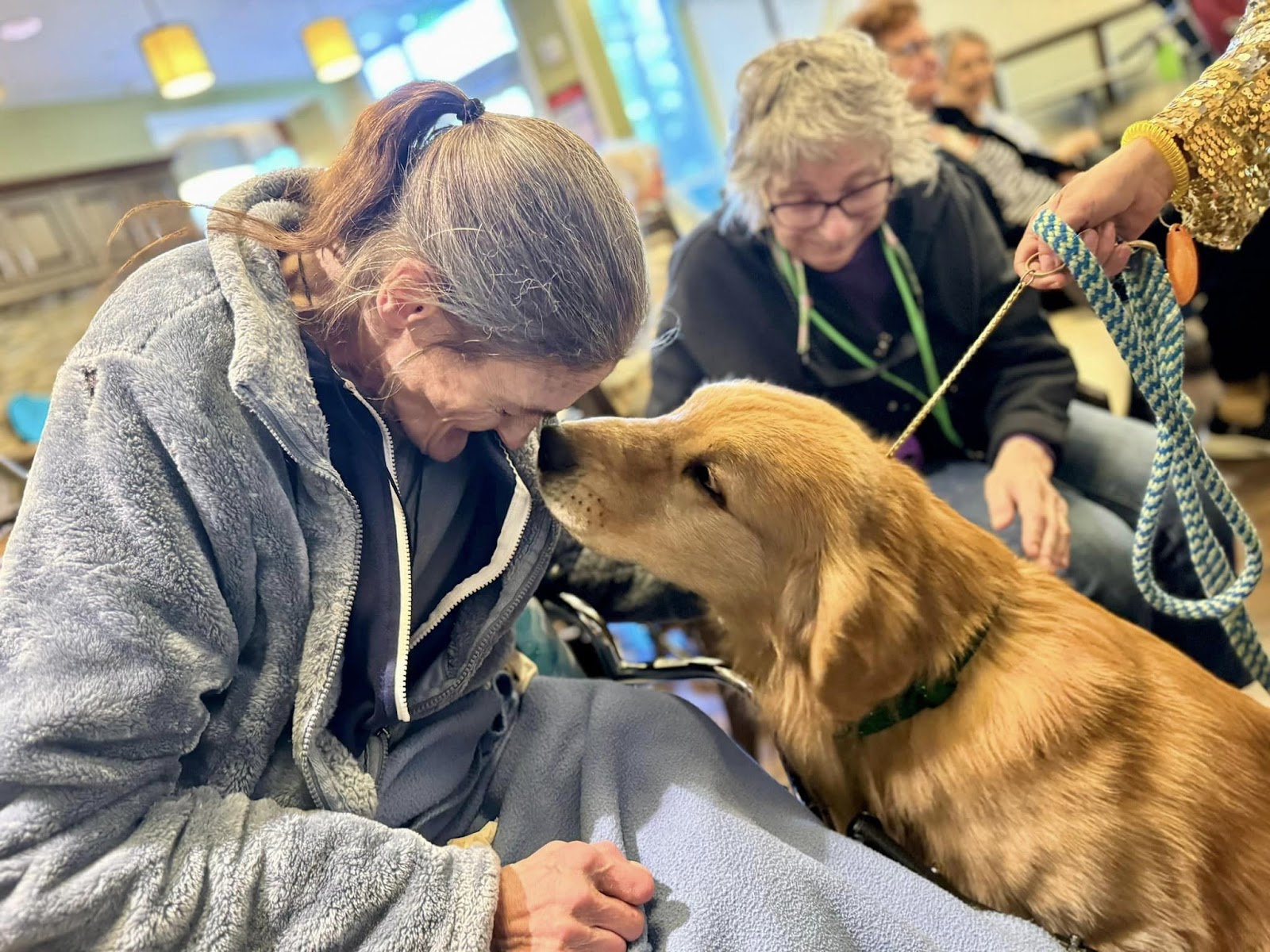 A woman touching her head to the nose of a golden retriever dog