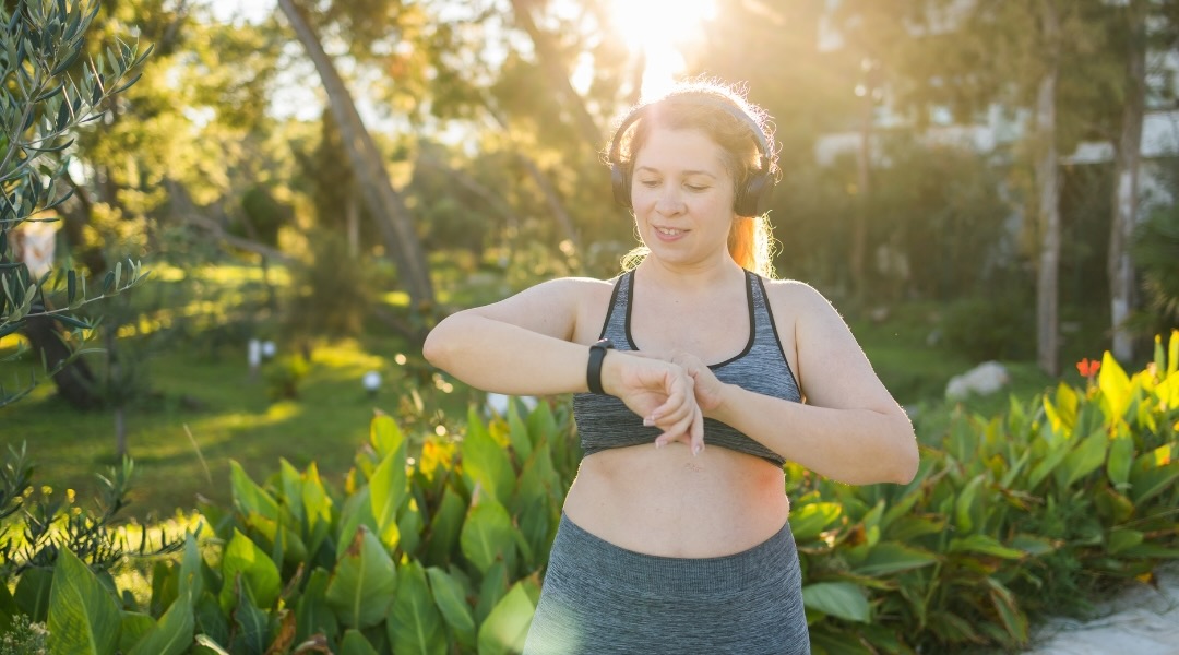 woman checking the time or heart rate on a smartwatch. Exercising or running outdoors to lose weight.