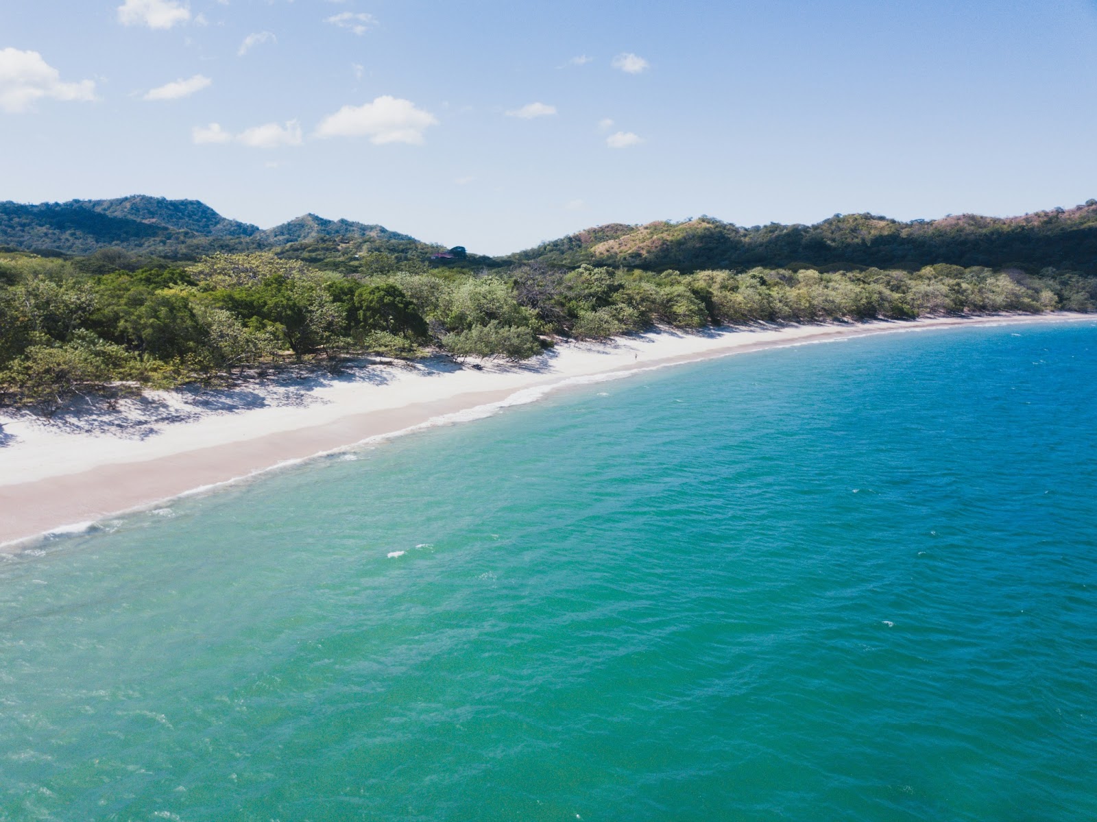 Guanacaste’s sandy beach with a lush rainforest in view.