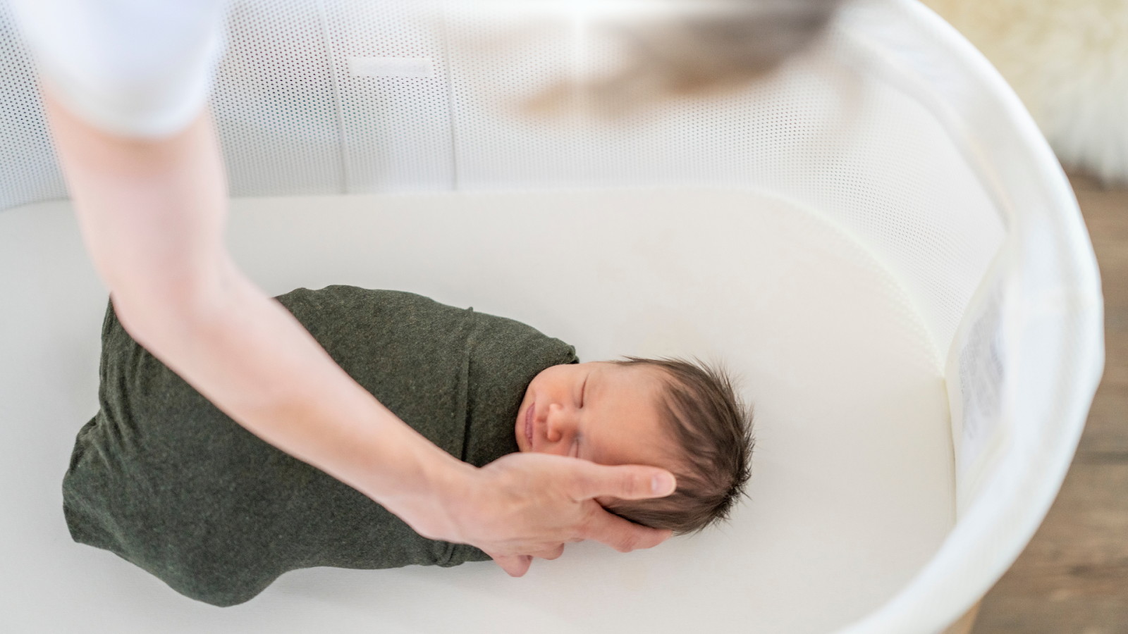 Newborn baby sleeping in a smart bassinet, mom is rubbing baby // Healthier Baby Today