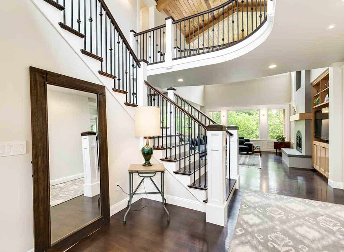 Foyer with a large full-length mirror, a side table, and an elaborate staircase.