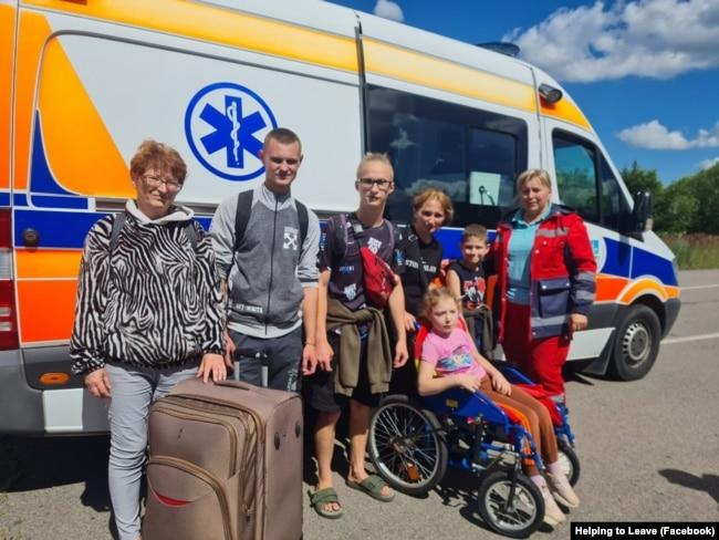 A group of people standing in front of a bus

Description automatically generated