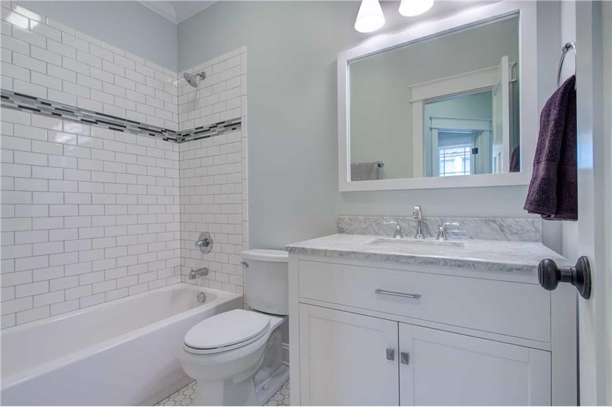 This bathroom is equipped with a single sink vanity, a toilet, and a tub and shower combo accentuated with a subway tile backsplash.
