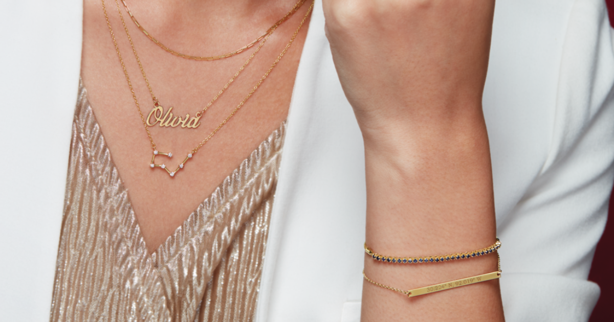 A woman with three necklaces of a diamond constellation, nameplate with the name "Olivia" and a thin gold chain necklace