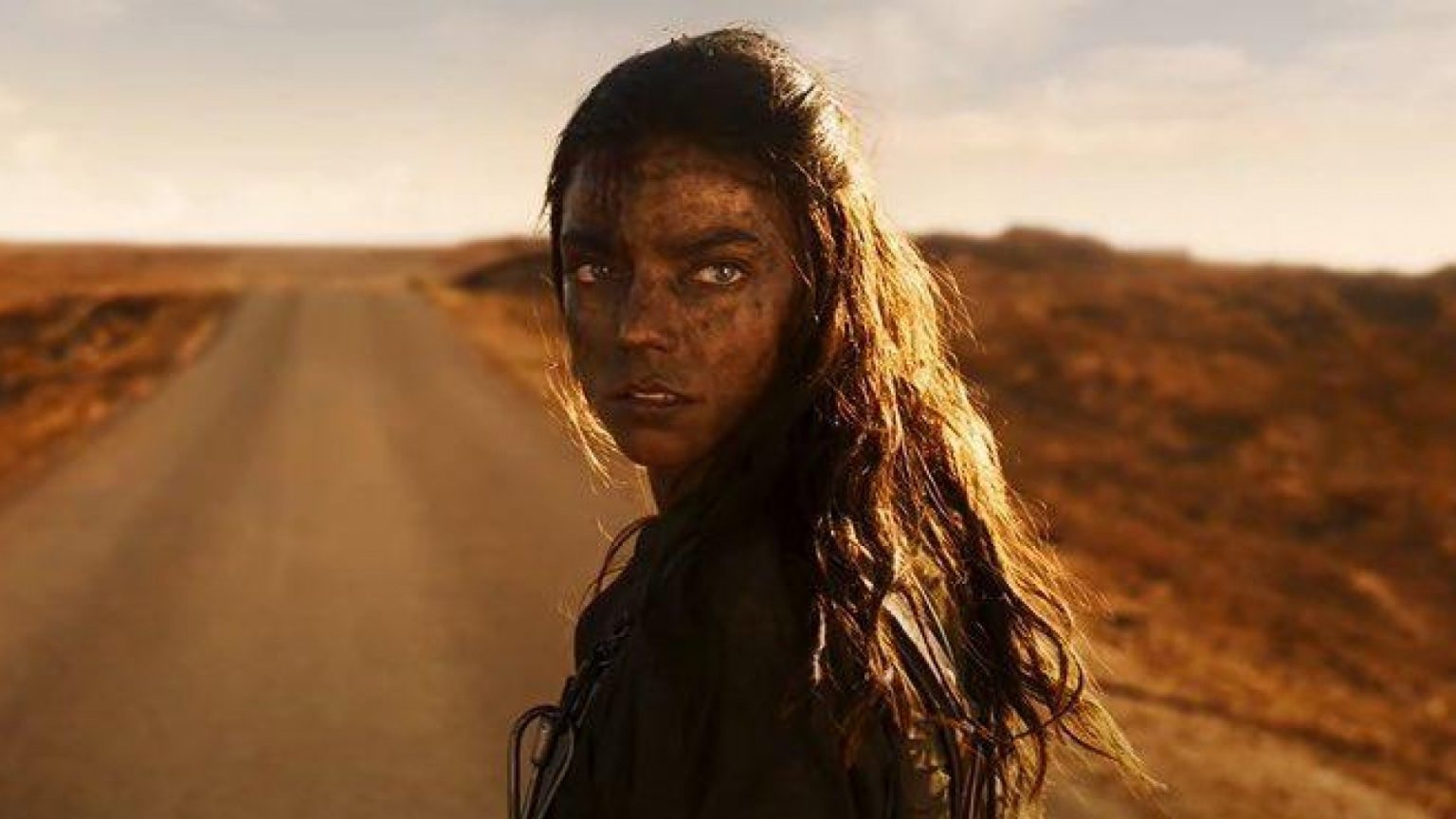 Anya Taylor-Joy interpretando a Furiosa, parada en el medio de la carretera, en Furiosa: de la Saga Mad Max.