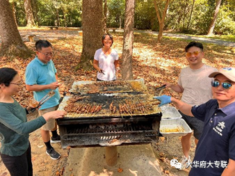 A group of people standing around a barbecue

Description automatically generated