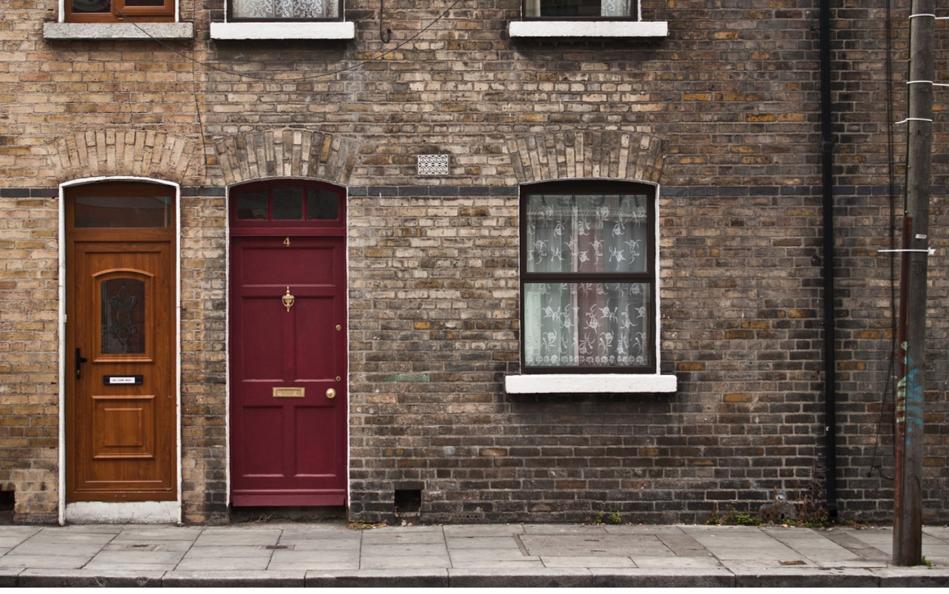 A red door and window on a brick buildingDescription automatically generated