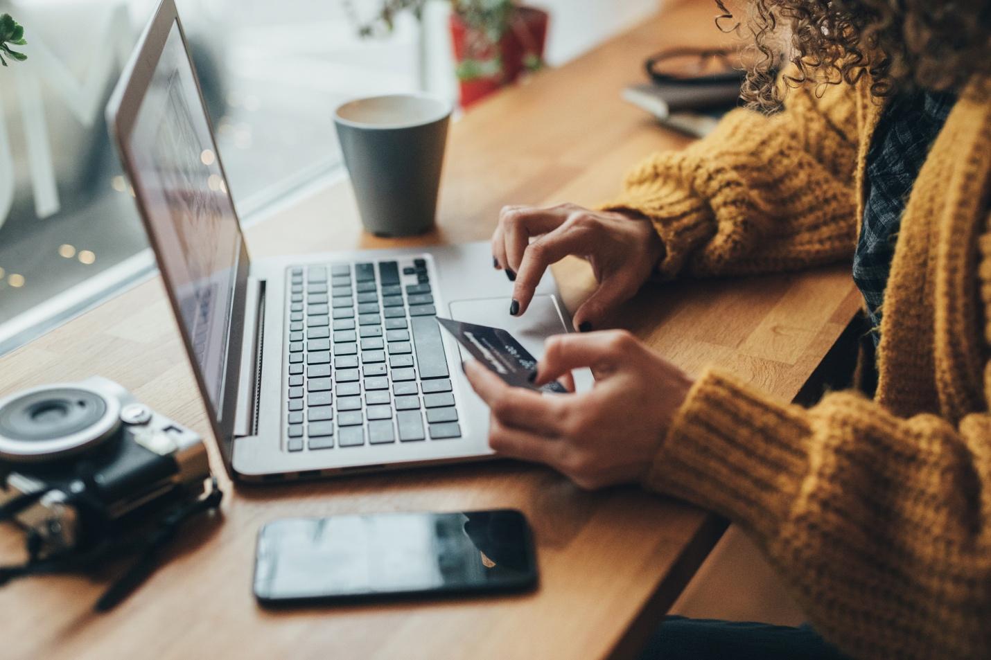 Person holding credit card using laptop