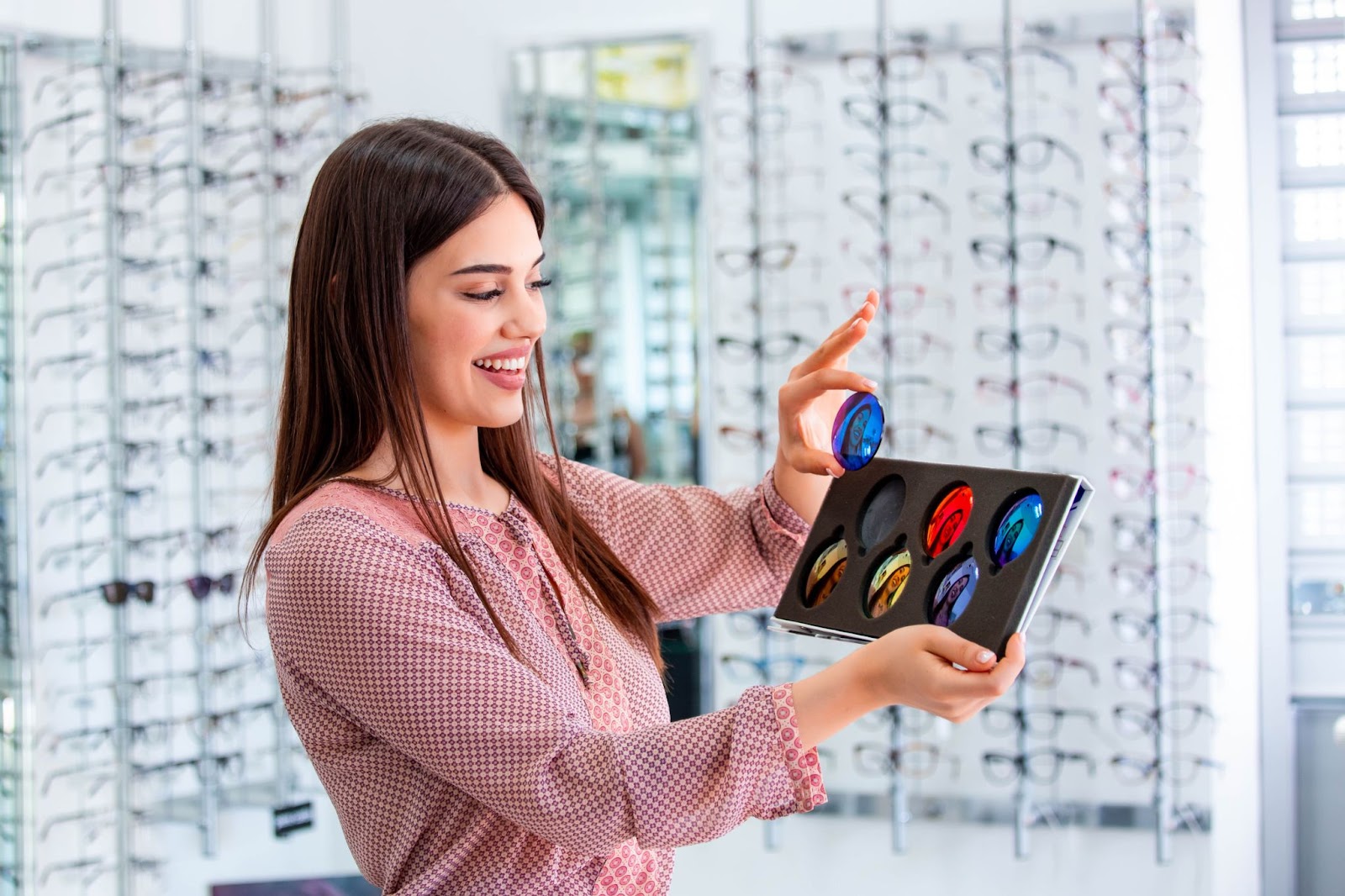 Attractive young female doctor in ophthalmology clinic showing different polarized lens.