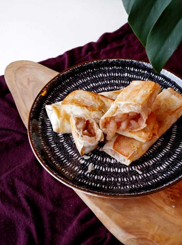 Strudels aux pommes sur une assiette décorative, avec un strudel coupé pour révéler la garniture aux pommes.