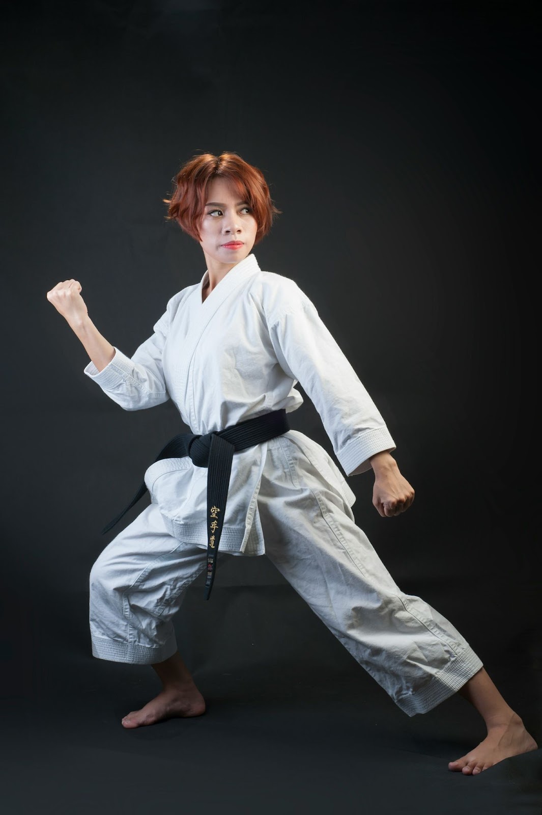 A woman in white clothes and a black belt.