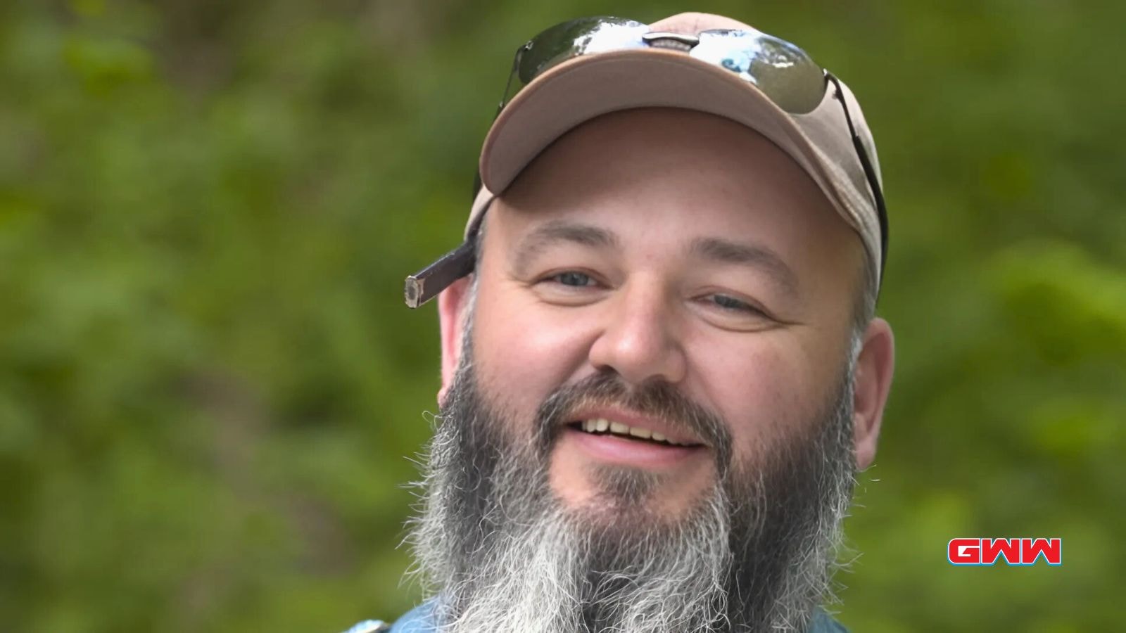 Jerry with cap and sunglasses smiling in the outdoors.