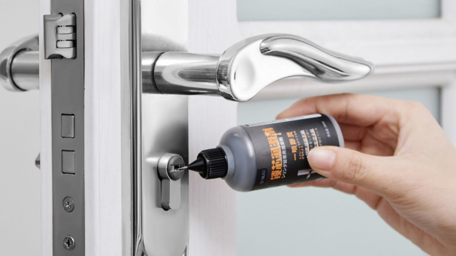 Applying lubricant for proper lock maintenance on a door lock.