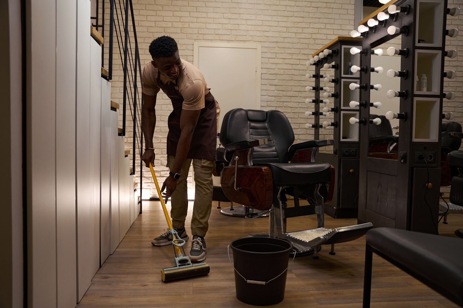 A man cleans his living room space with a mop and bucket.