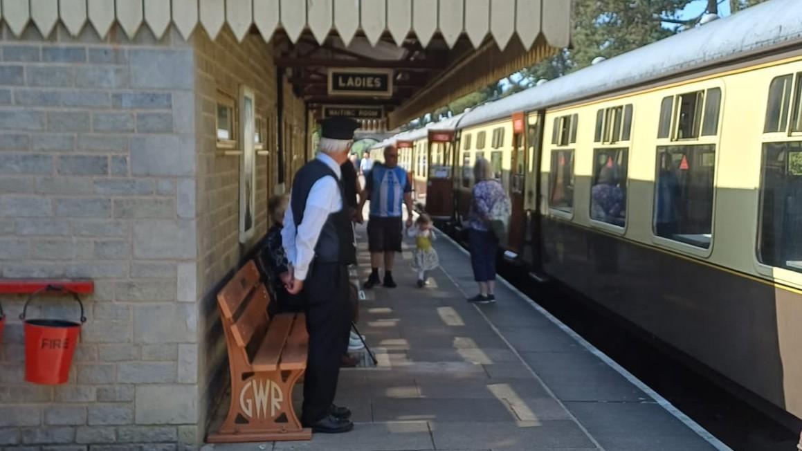 A person standing on a platform next to a train

AI-generated content may be incorrect.