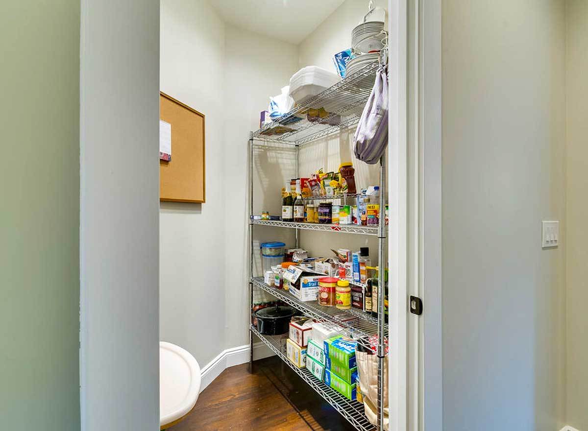 A walk-in pantry with a metal shelving unit filled with groceries.