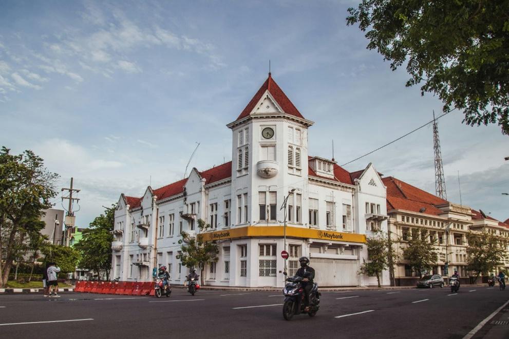 A white building with a clock tower and a motorcycle on the road AI-generated content may be incorrect.