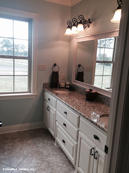 Primary bathroom with a large white vanity equipped with double sinks and a rectangular framed mirror.