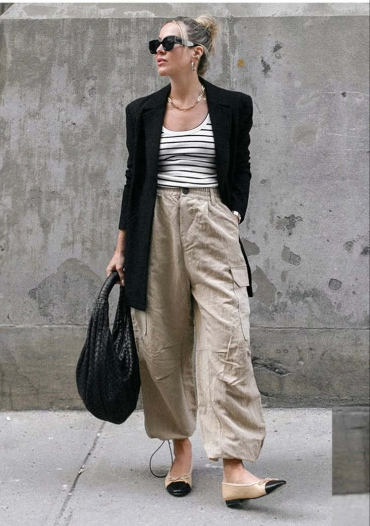 wanita memakai cargo krem, tank top belang,blazer hitam, dan tas