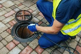 A person in a yellow vest and gloves working on a sewer
AI-generated content may be incorrect.