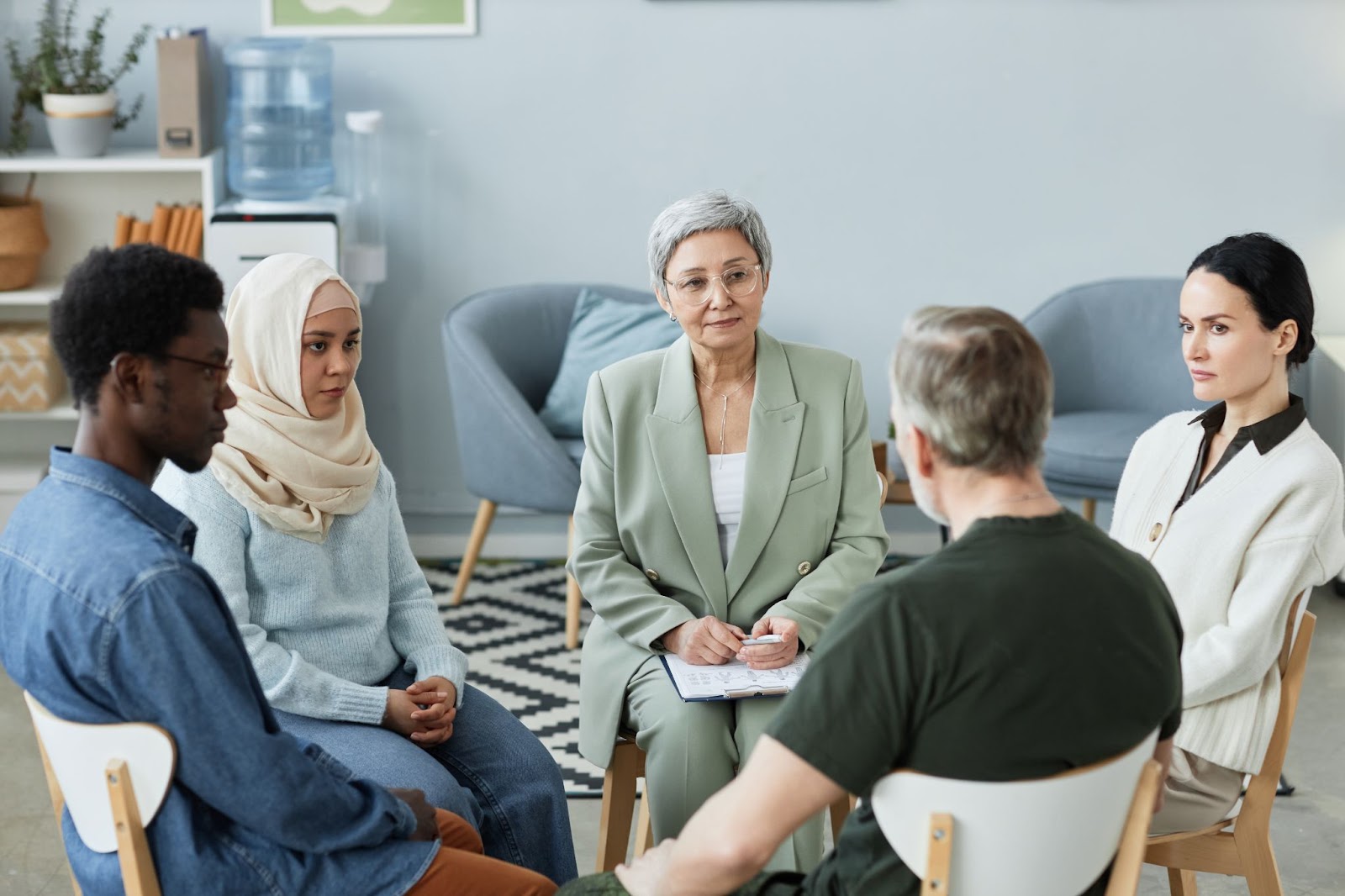 People sitting in a circle next to a trained professional. 