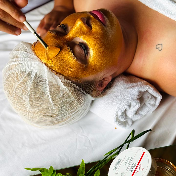 Tratamento de beleza facial com máscara dourada para uma pele revitalizada, com uma mulher relaxando em um spa de luxo.