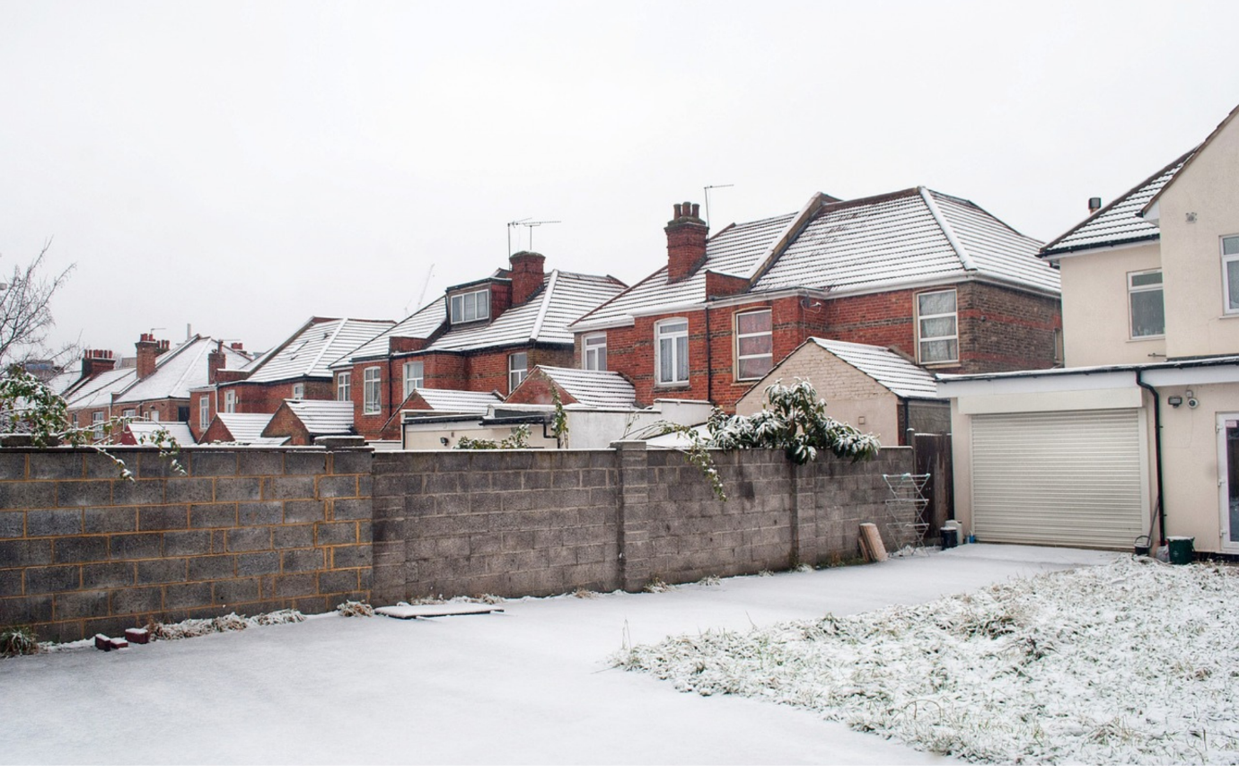 A snow covered yard and brick houseDescription automatically generated