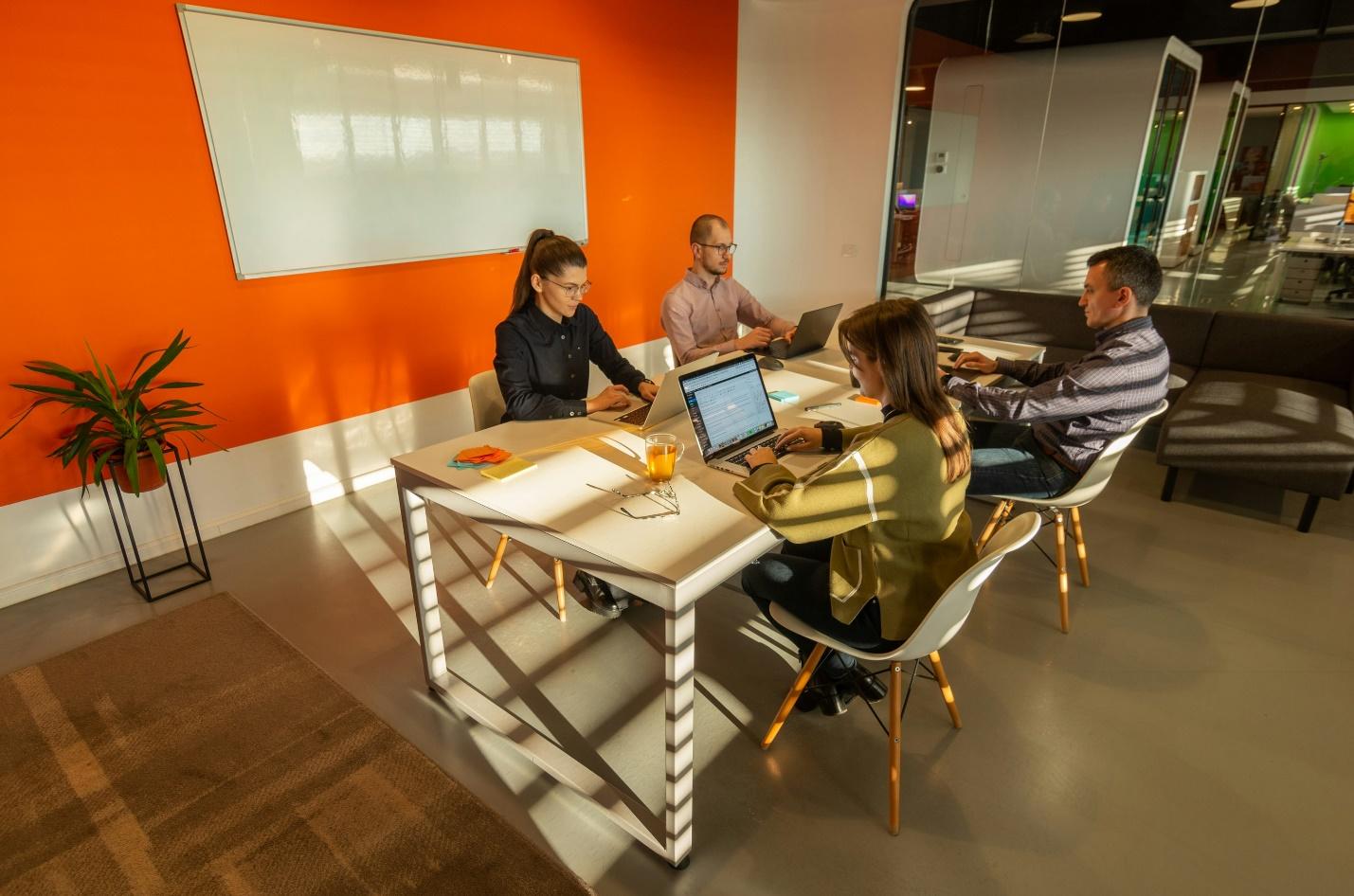 a group of people sitting around a table with laptops