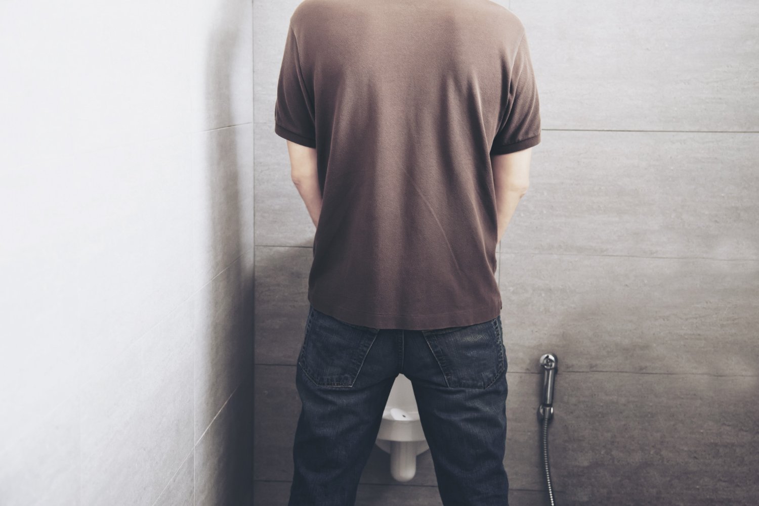 pria sedang buang air kecil di toilet berdiri sebagai ilustrasi kondisi kencing berbusa