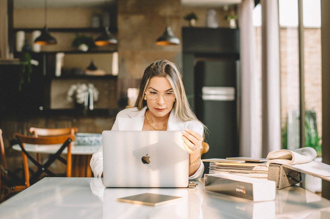 Free A woman sitting at a table with her laptop Stock Photo