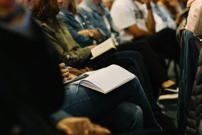 A group of people sitting in a room taking notes.