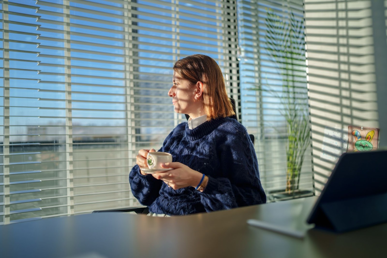 a woman sitting in front of the window covered with window blinds