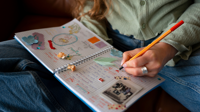 A person journaling and capturing ideas in a notebook with pictures and patterns