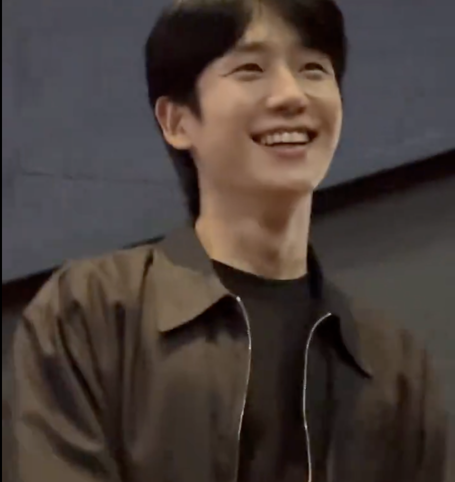 This contains an image of Jung Hae In on a brown jacket smiling