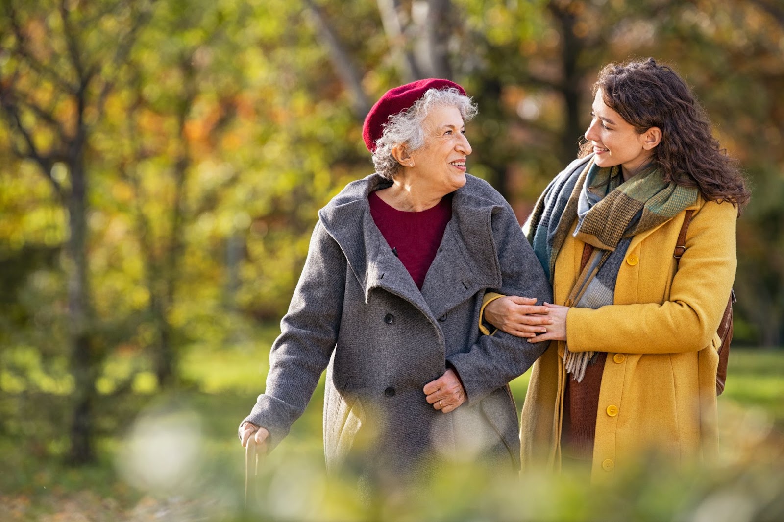 A mother and her adult daughter walk through the park together